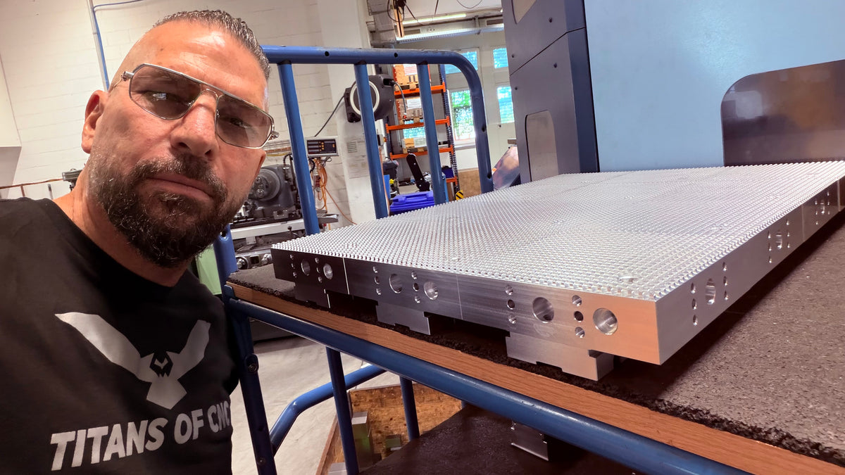 Facility visit photo beside a large machined fixture plate